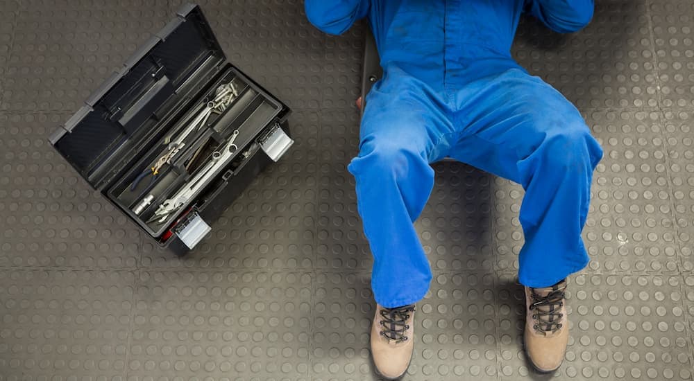 A mechanic is shown underneath a vehicle at an auto repair shop.
