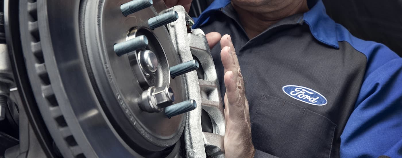 A Ford mechanic is shown inspecting a vehicle.