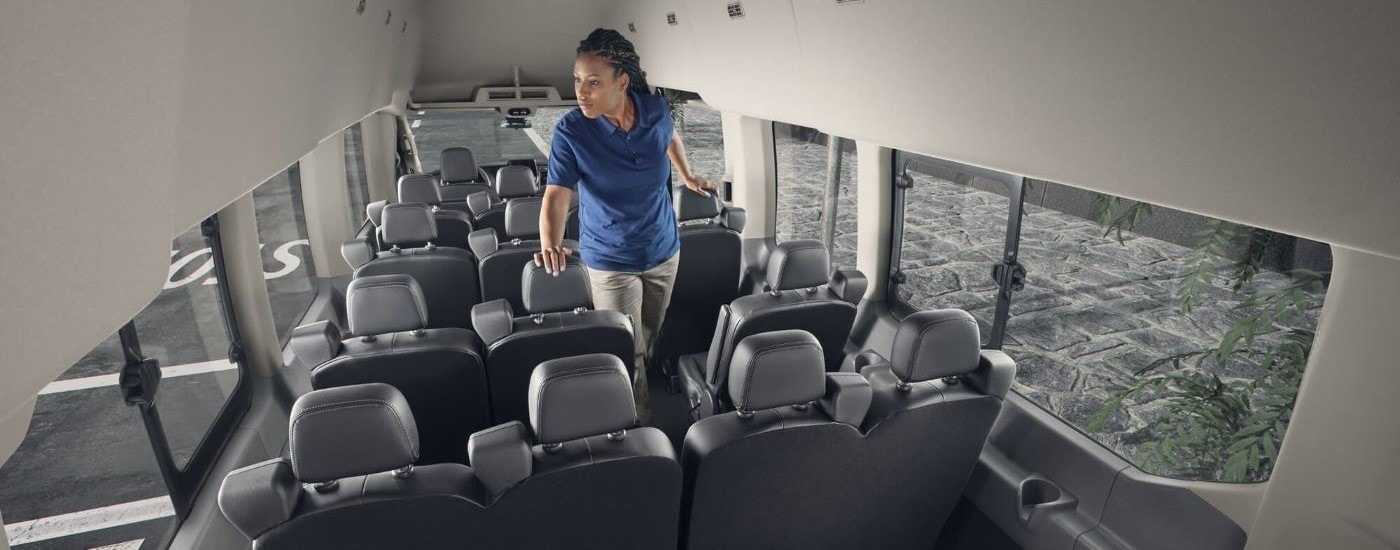 A woman walking down the aisle of a 2023 Ford Transit for sale.