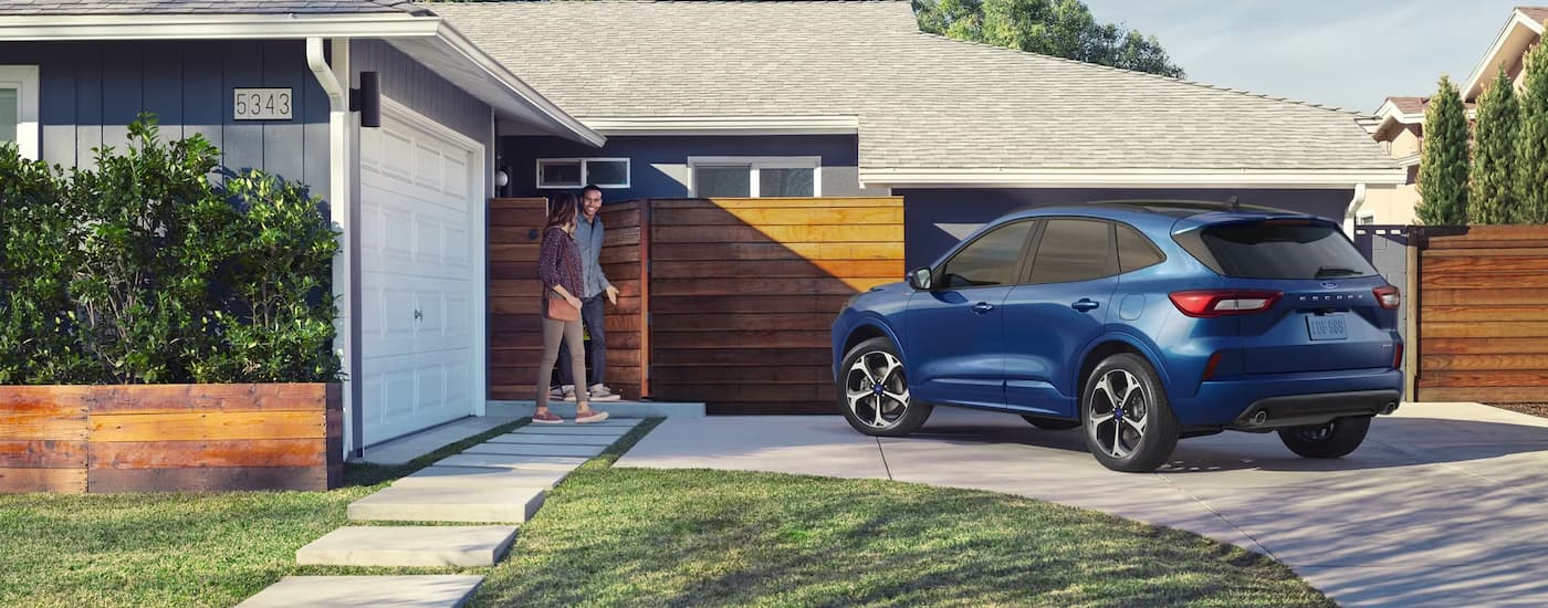 A blue 2023 Ford Escape parked in the driveway of a modern home.