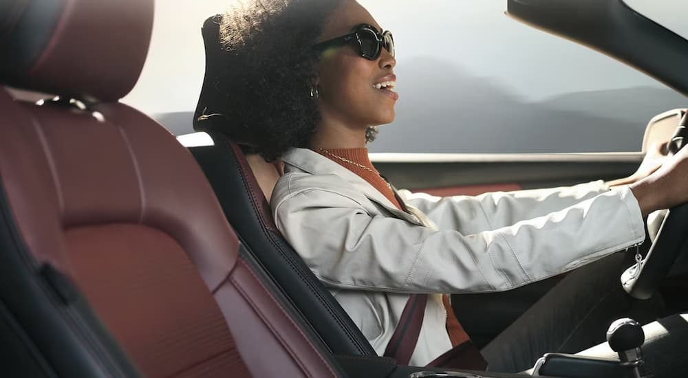 A woman driving a 2024 Ford Mustang with the top down.