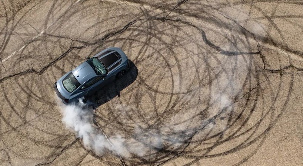 Aerial view of a silver 2024 Ford Mustang doing donuts in an empty lot.
