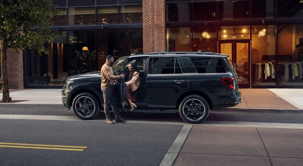 A black 2024 Ford Expedition Stealth Edition parked on a city street in front of a shop.