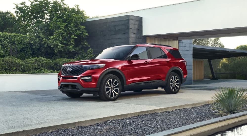 A red 2023 Ford Explorer ST-Line parked in the driveway of a modern house.