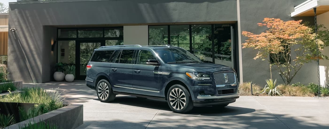 A blue 2023 Lincoln Navigator parked in the driveway of a modern home.