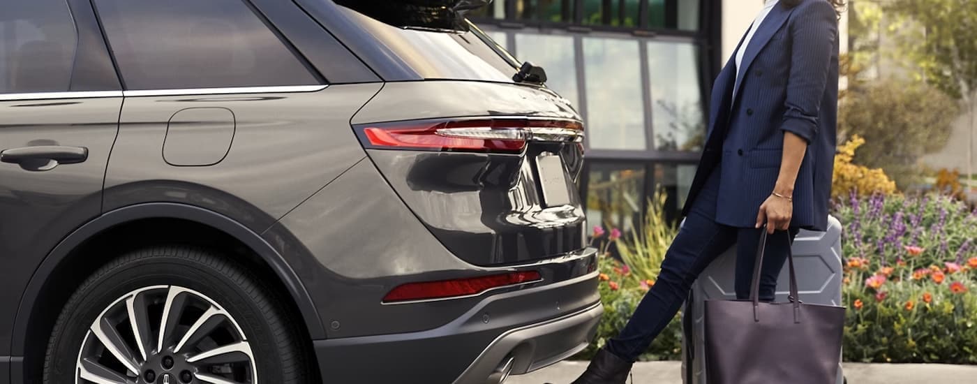 A woman using the hands-free liftgate feature on a grey 2024 Lincoln Corsair.
