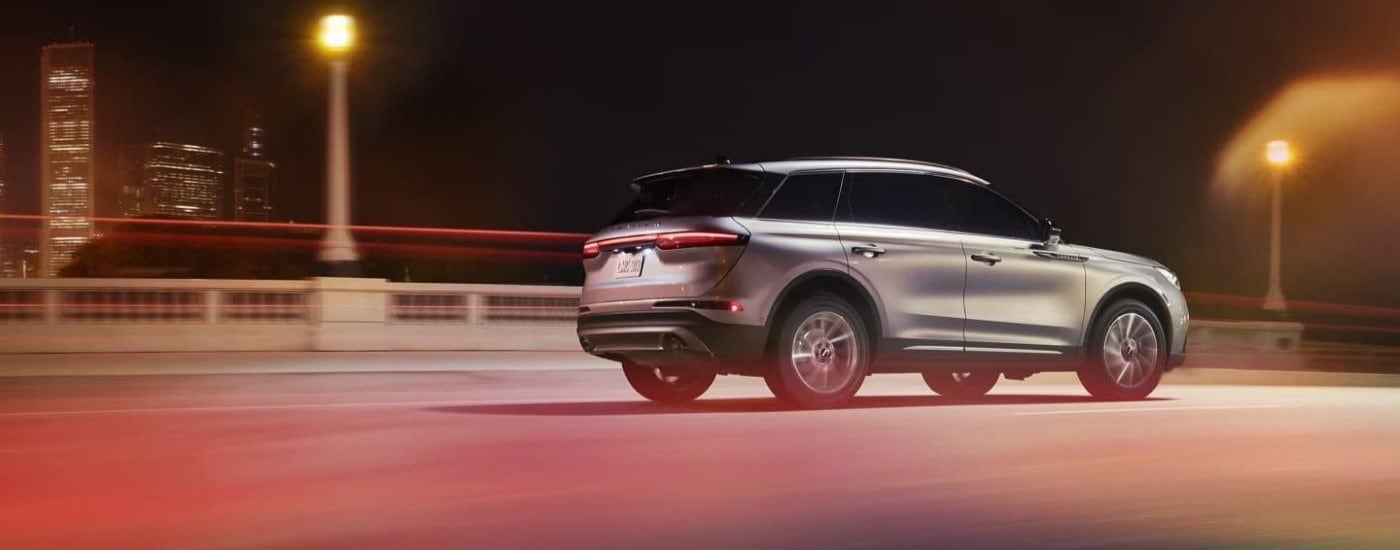 A silver 2023 Lincoln Corsair driving on a city street at night.