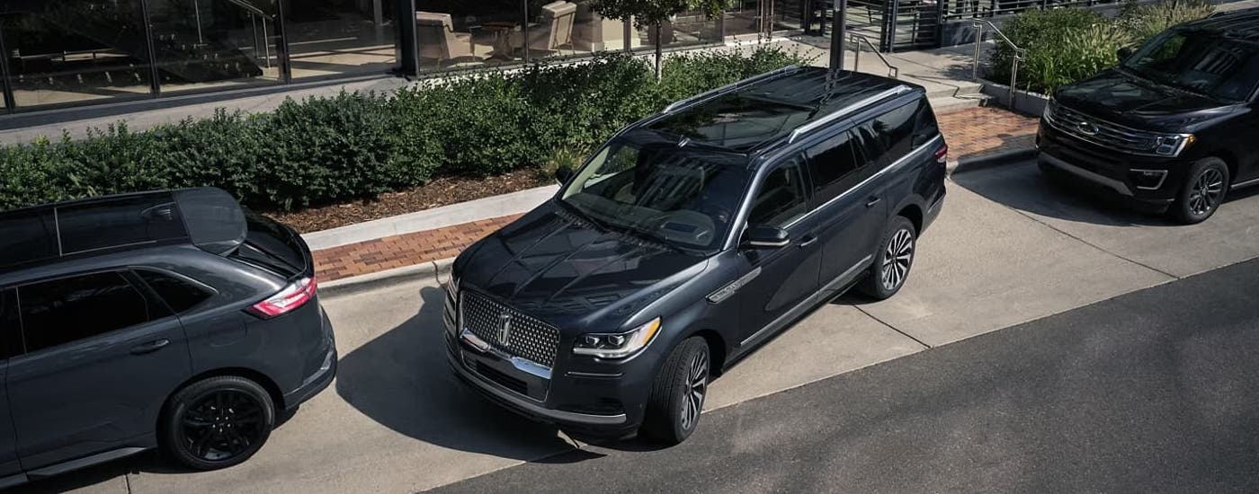 A grey 2024 Lincoln Navigator parallel parking on the side of a city street.