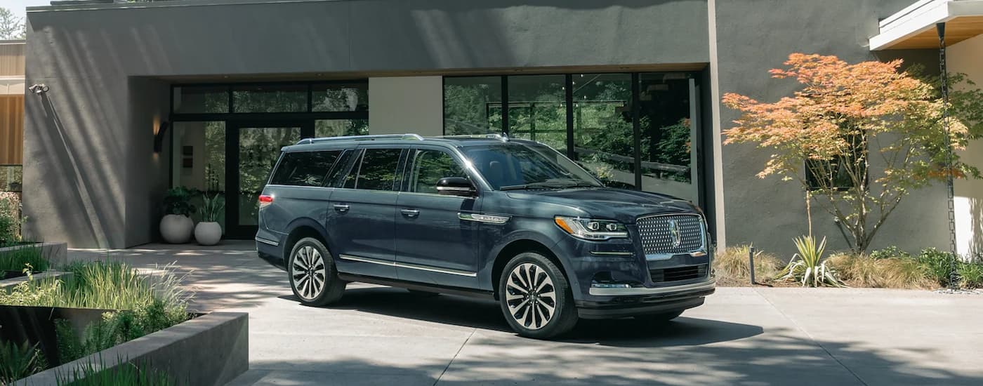 A blue 2023 Lincoln Navigator parked in the driveway of a modern home after leaving a Lincoln dealer near you.