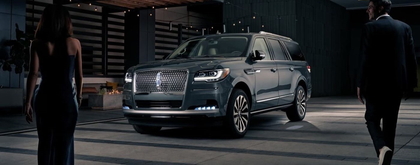 A grey 2023 Lincoln Navigator parked in front of a modern building at night after leaving a Lincoln dealer near Queens.