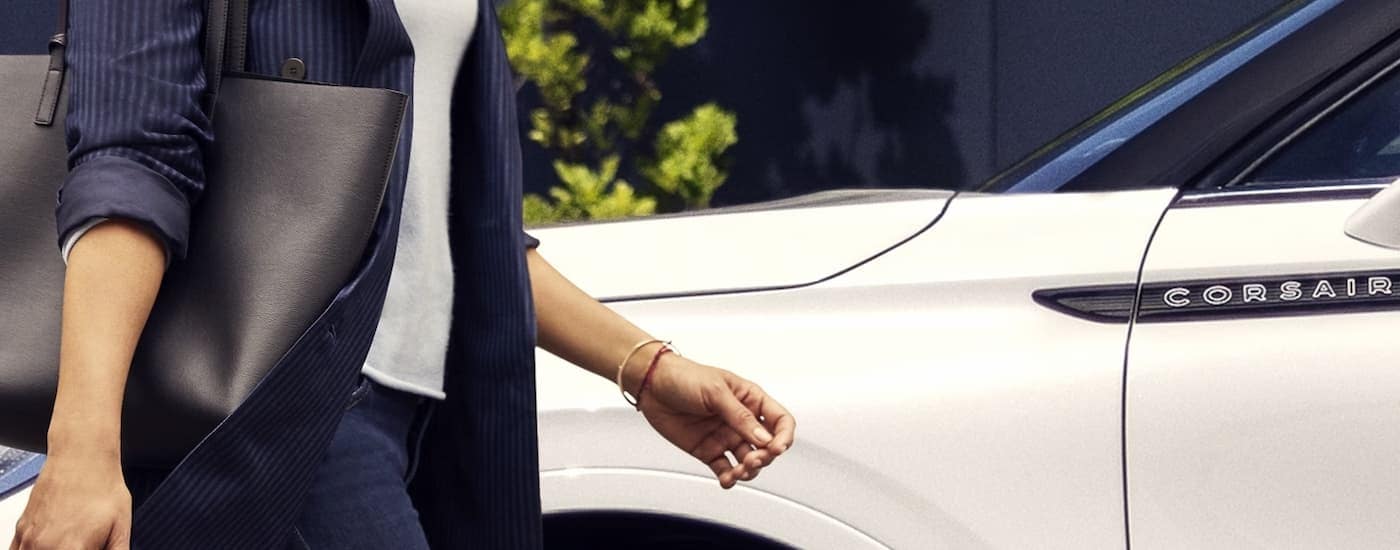 Close-up of a woman walking by a white 2024 Lincoln Corsair.