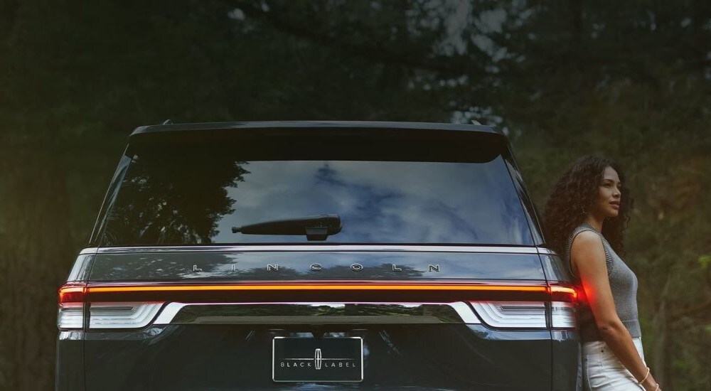 A woman leaning against a black 2024 Lincoln Navigator Black Label.