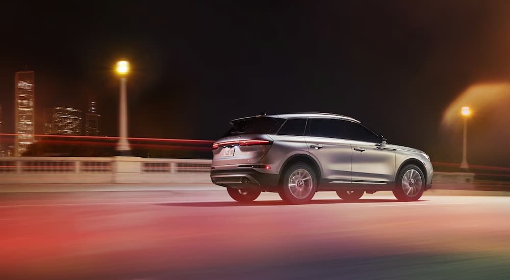 A silver 2024 Lincoln Corsair driving on a city highway at night.