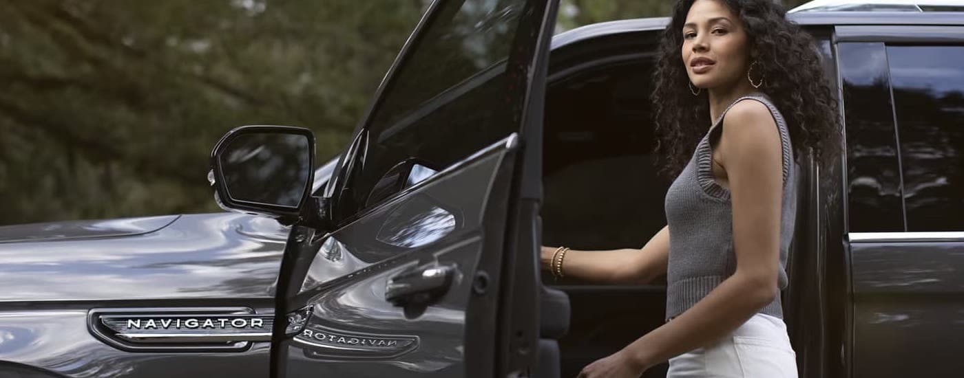 A woman opening the drivers side door on a grey 2024 Lincoln Navigator for sale.