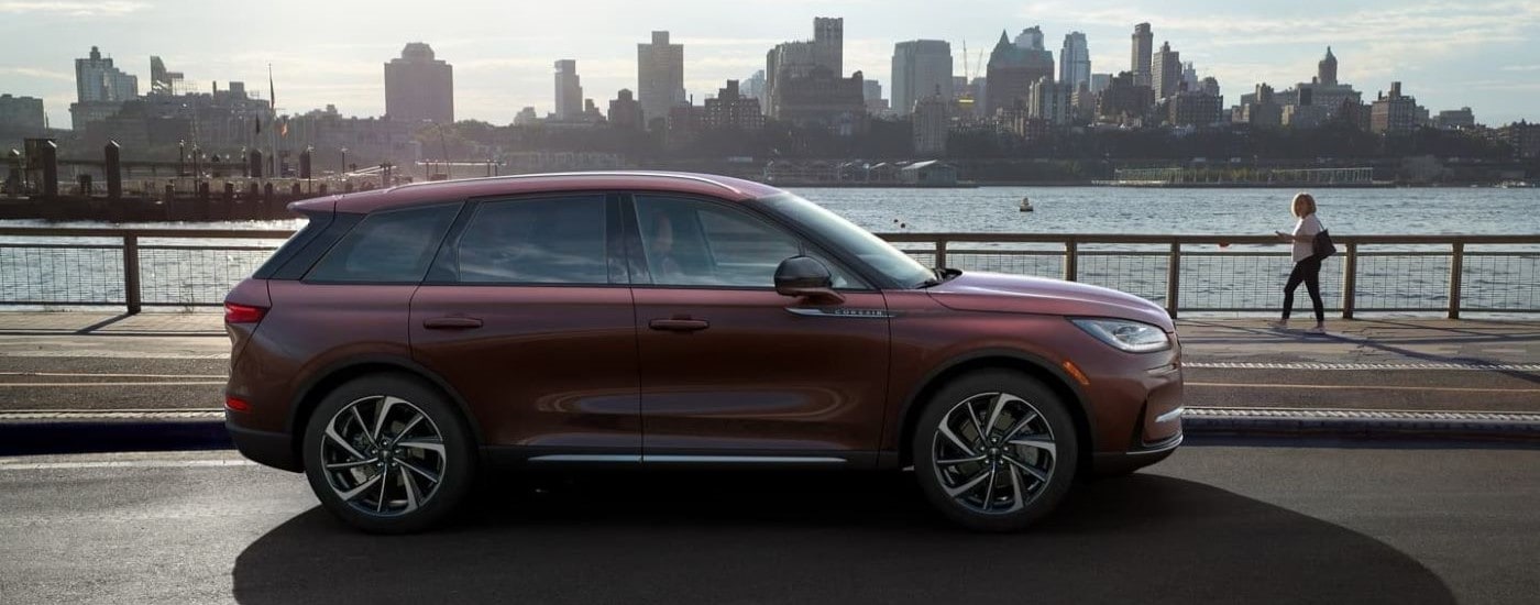 A maroon 2023 Lincoln Corsair parked near a body of water in a city park.