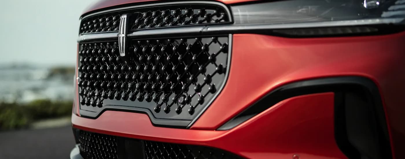 A close up of the grille on a red 2024 Lincoln Nautilus at a Lincoln dealer.