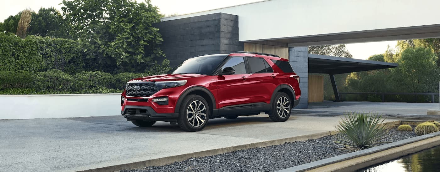 A red 2023 Ford Explorer ST parked in the driveway of a modern home.
