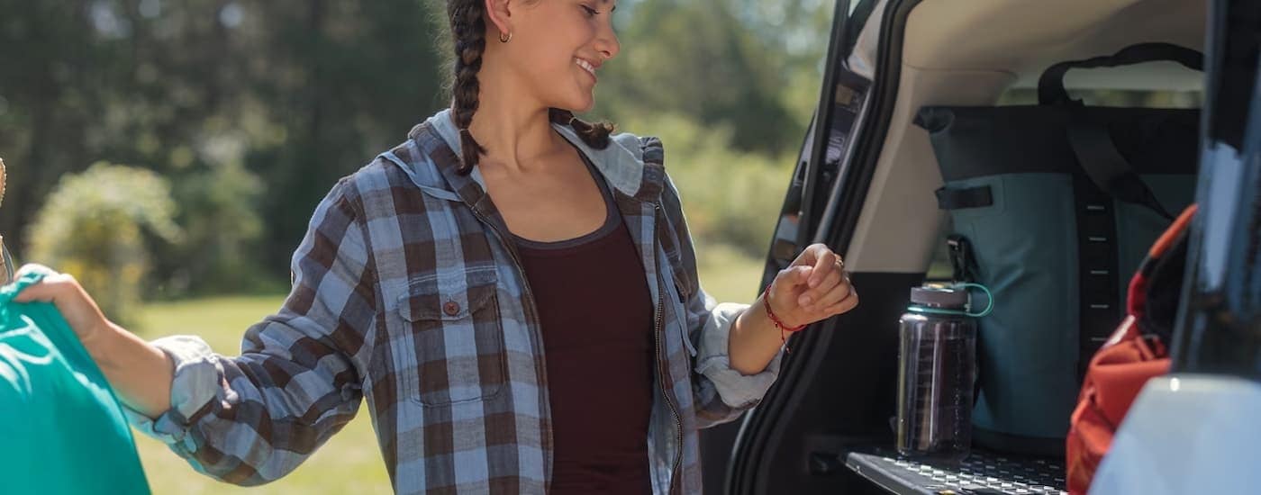 A woman packs camping gear into the rear of a 2023 Ford Bronco Sport.