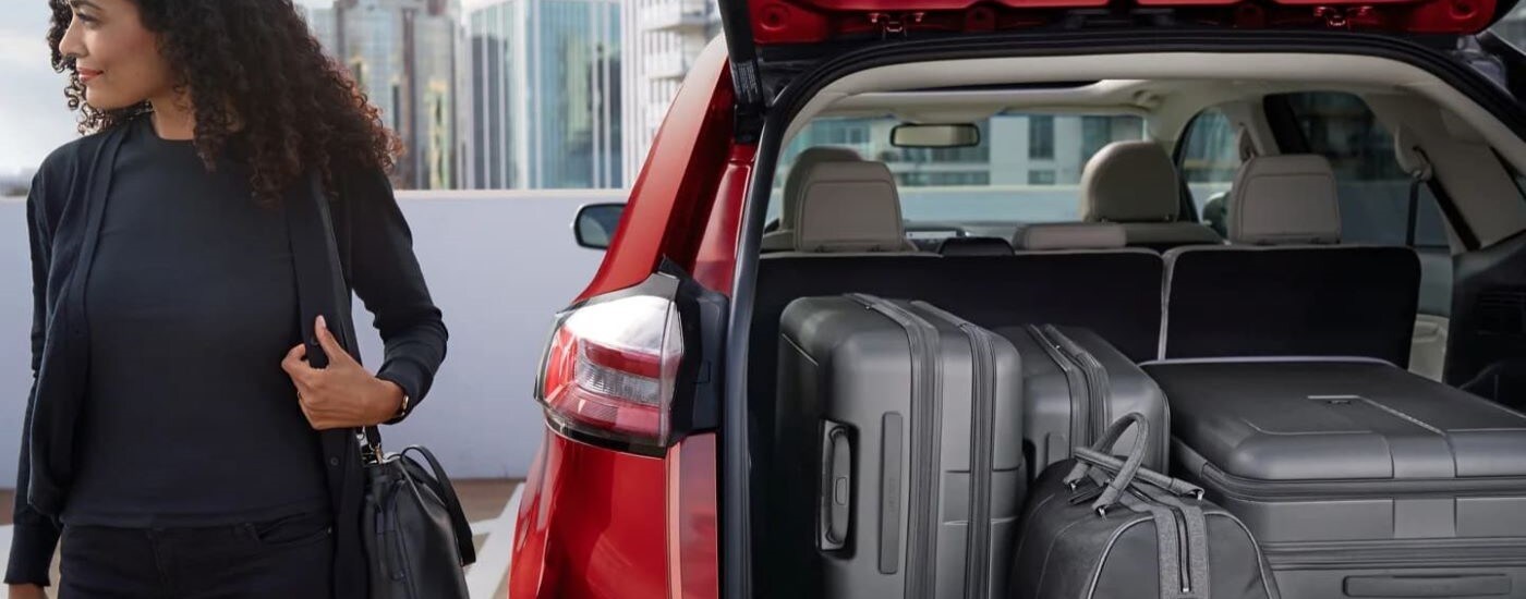 Matching grey luggage stacked neatly in the trunk of a red 2023 Ford Edge.