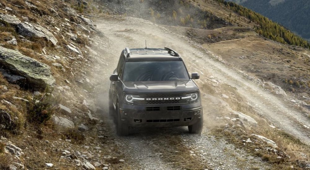 A grey 2023 Ford Bronco Sport Badlands kicking up dust while off-roading down a mountain.