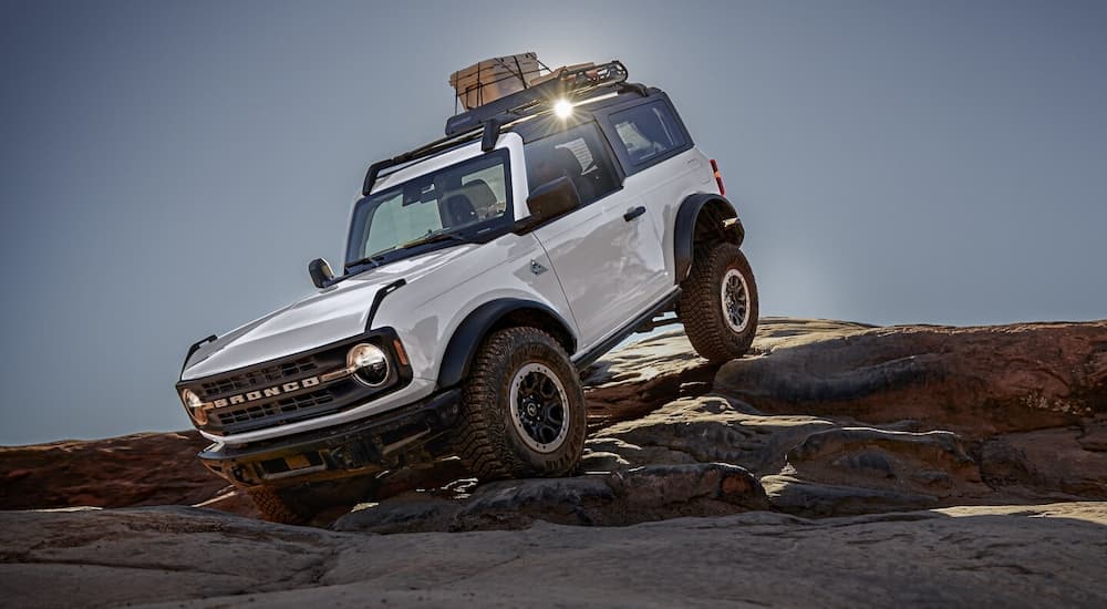 A white 2024 Ford Bronco off-roading down steep rocks after leaving a Ford dealer.