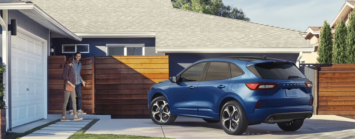 A blue 2023 Ford Escape ST is shown from a rear angle parked in a driveway.