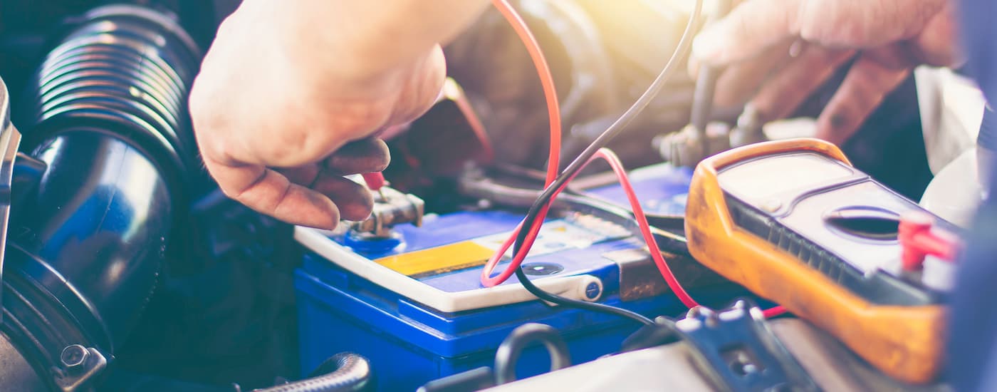 A mechanic is shown using a multimeter on a battery at a Ford service center near Staten Island.