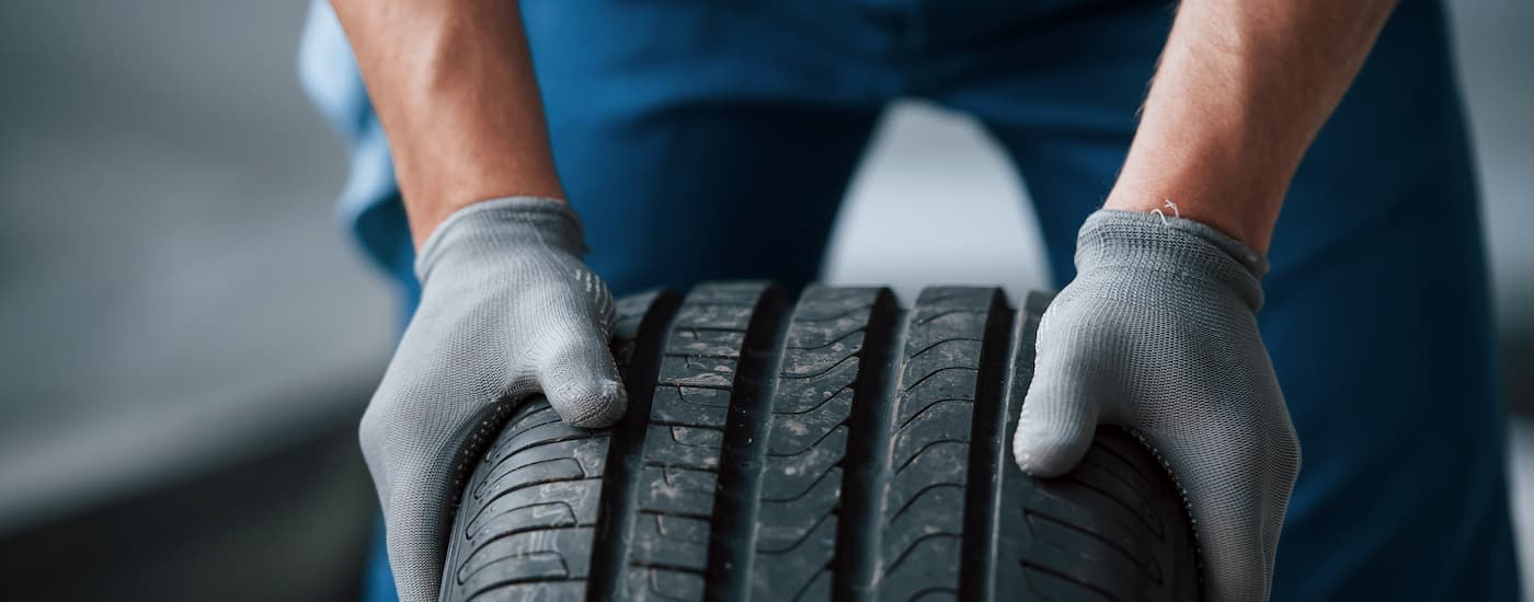 A mechanic is shown rolling a tire through shop.