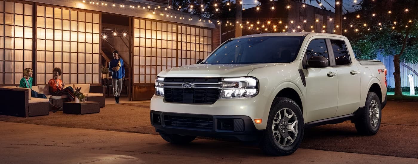 A white 2024 Ford Maverick Lariat is shown parked underneath outdoor hanging lights.