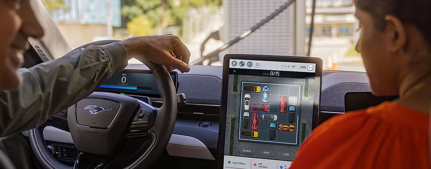 A close up of a family using the game feature on the infotainment screen in a 2023 Mustang Mach-E is shown.