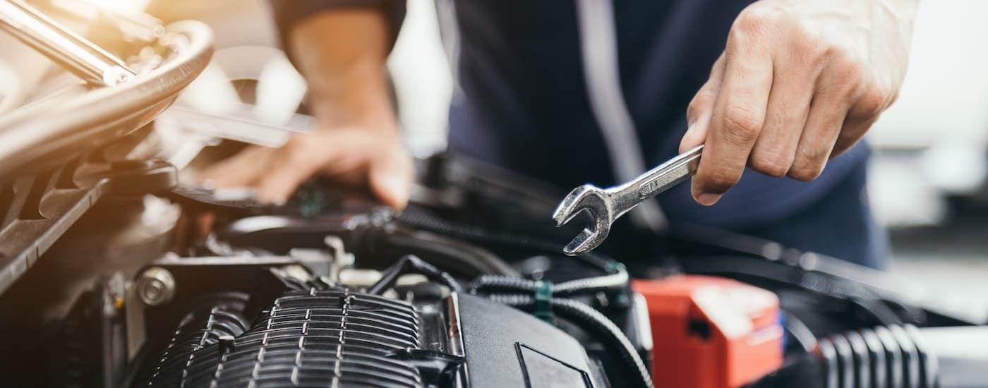 A mechanic holding a wrench over an engine at a Ford service center near Queens.