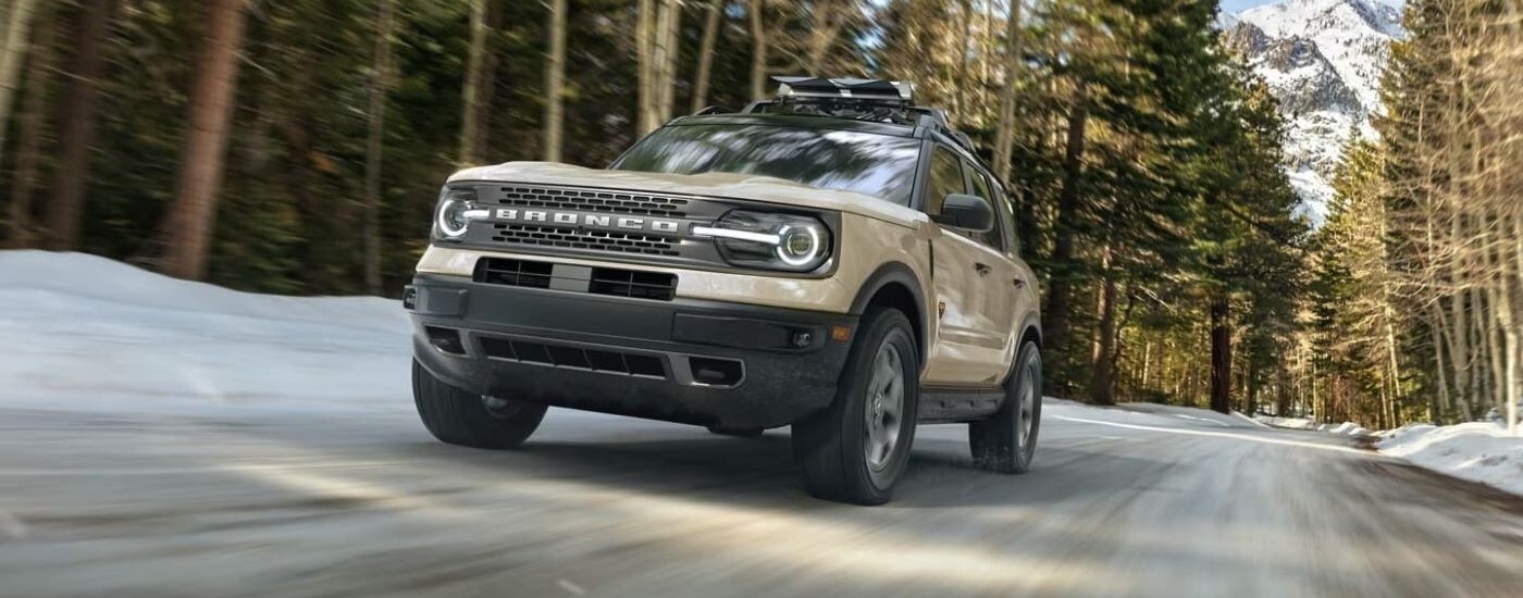A tan 2024 Ford Bronco Sport Badlands driving in a forest.