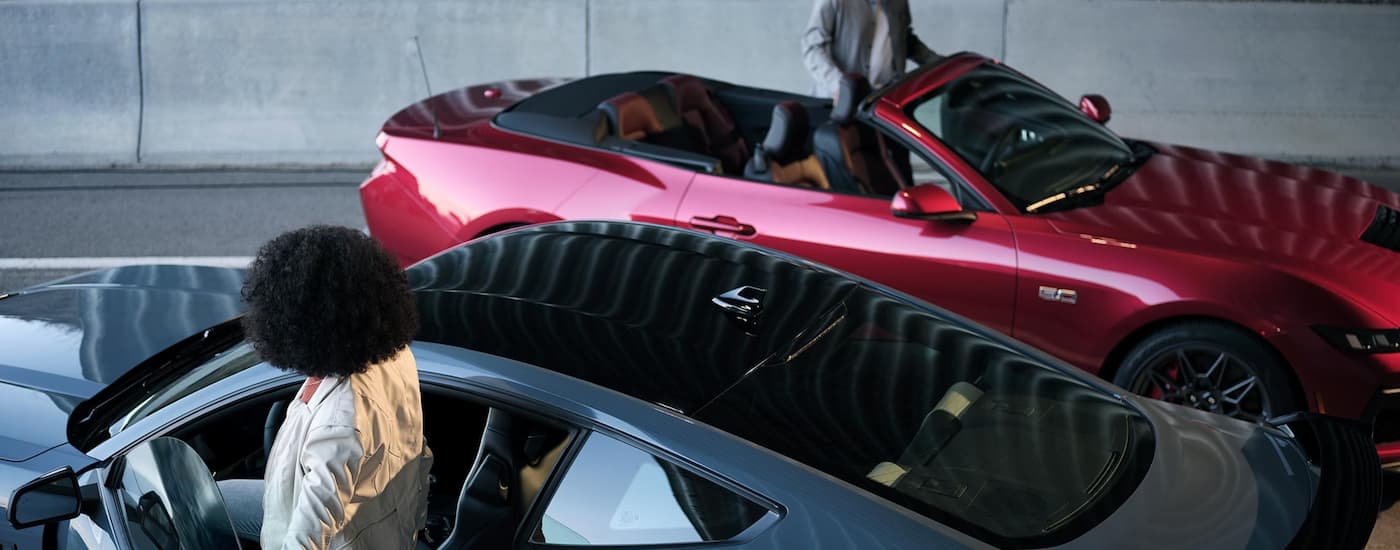 Ford Dealer in Brooklyn - 2024 Ford Mustang - red and blue.jpg A blue and a red 2024 Ford Mustang parked in a garage.