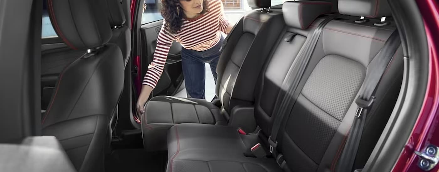 A woman is shown adjusting the rear seats in a red 2024 Ford Escape.