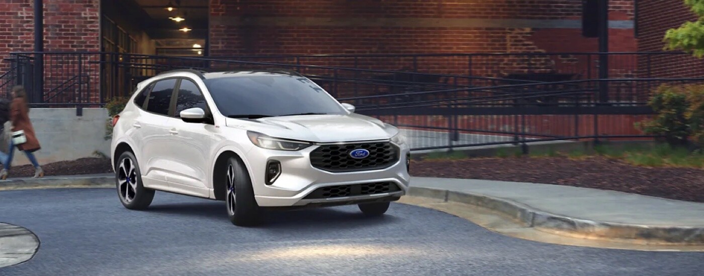 A white 2024 Ford Escape ST Line for sale is shown parked outside of a library.