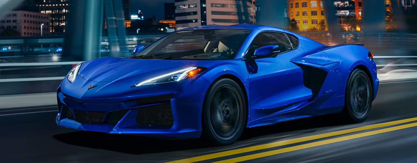 Blue 2026 Chevy Corvette E-Ray driving through a city at night