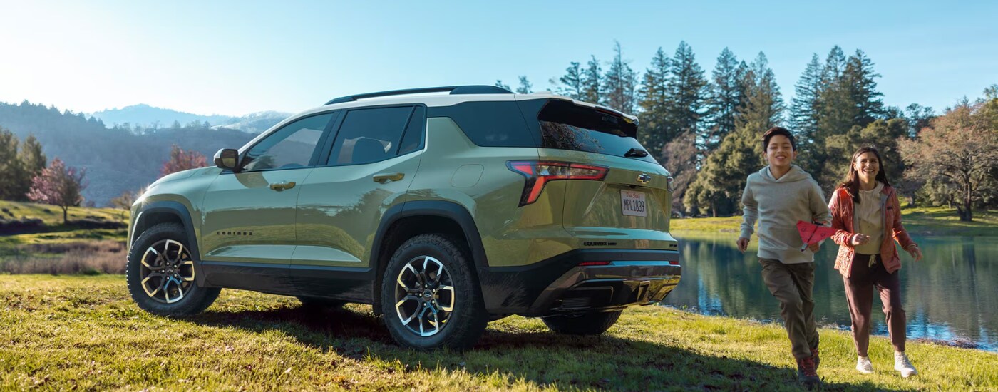 A family getting out of there green 2026 Chevy Equinox parked by a lake