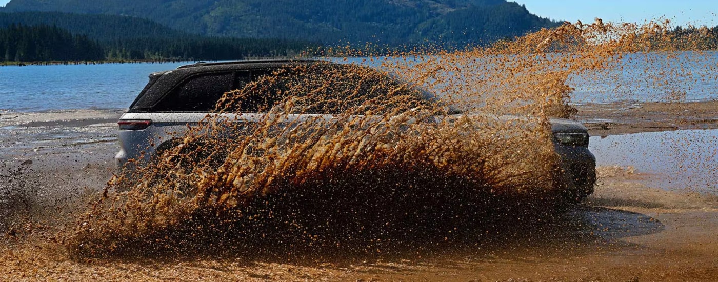 Silver 2026 Jeep GRand Cherokee driving through a muddy puddle