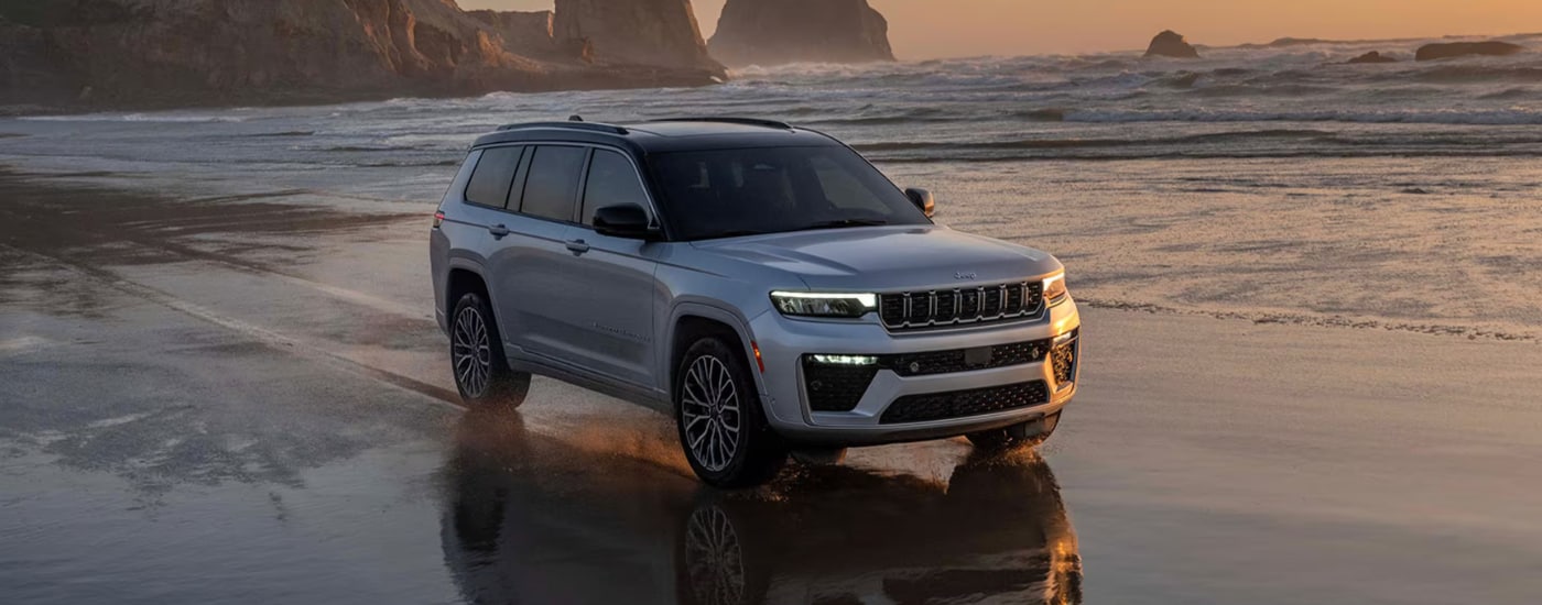 Silver 2026 Jeep Grand Cherokee driving along a beach