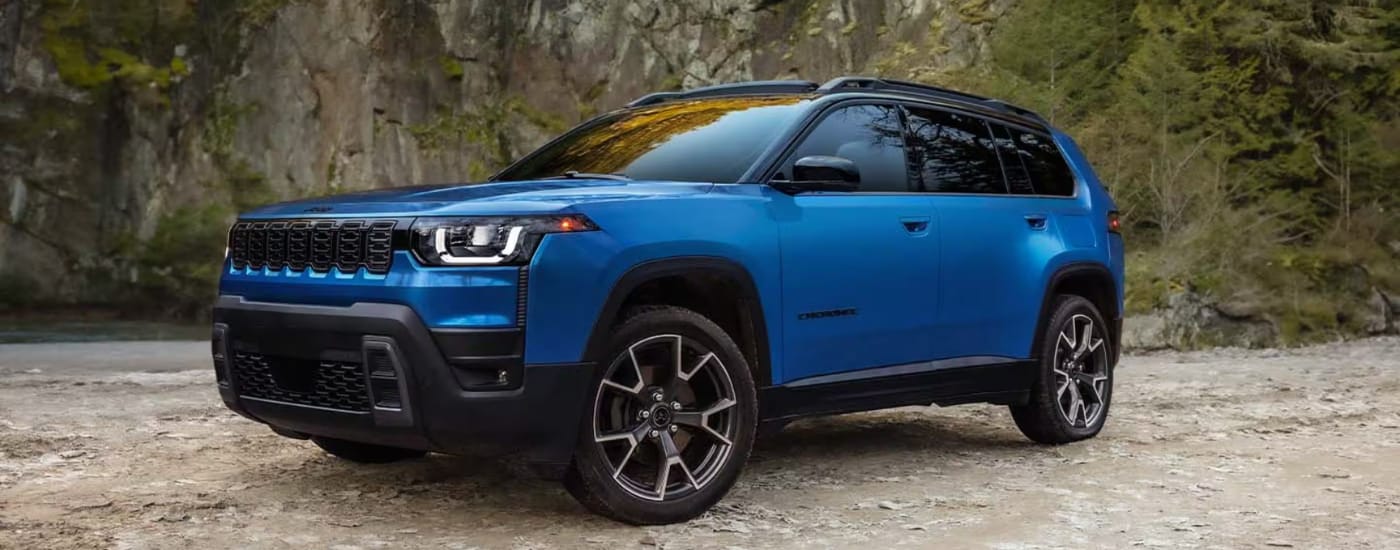 Blue 2026 Jeep Cherokee parked at an angle in front of a rockwall