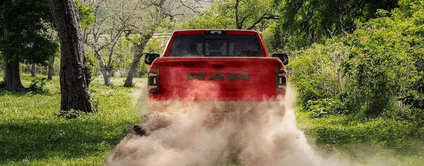 A red 2023 Ram 2500 Power Wagon is driving on a dusty dirt road.