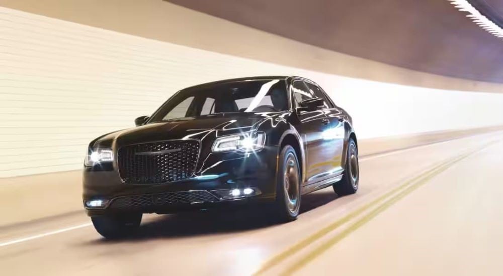 A black 2023 Chrysler 300 is shown driving in a tunnel after viiting a Chrysler dealer.