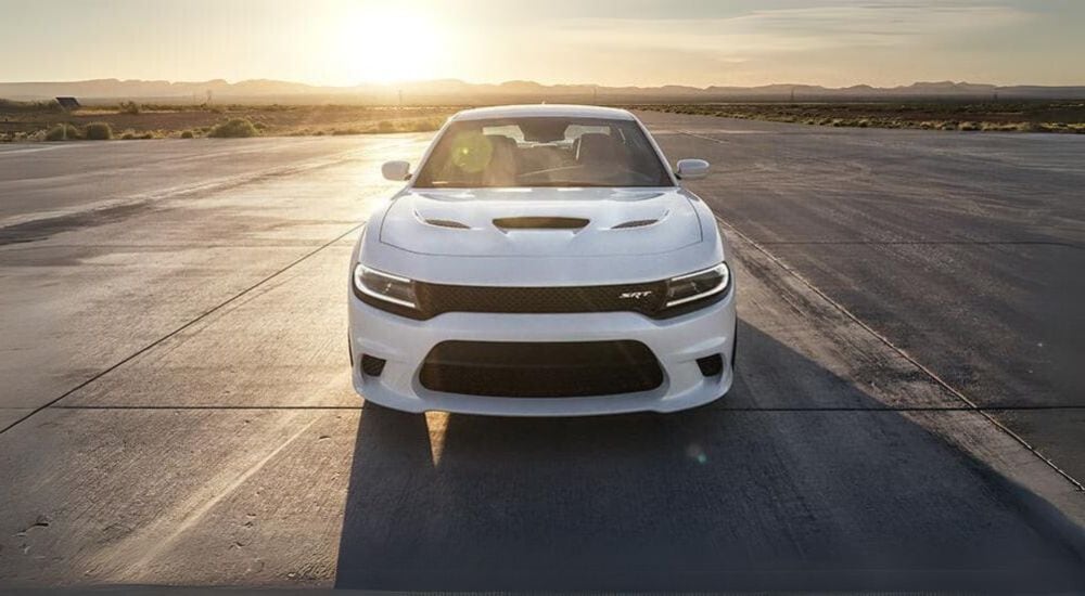 A white 2015 Dodge Charger SRT is shown on pavement after leaving a Dodge dealer.