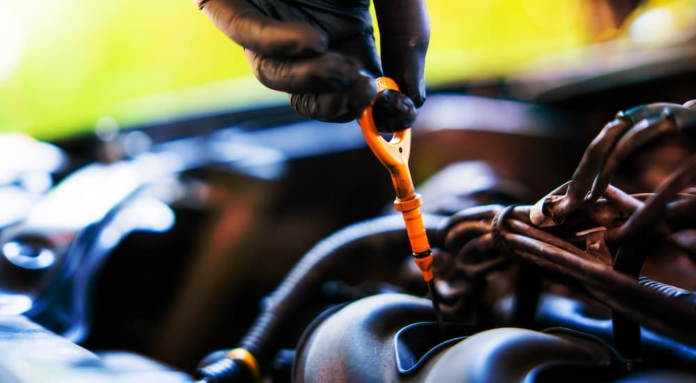 Close-up of a technician removing the engine oil dipstick to check oil levels.