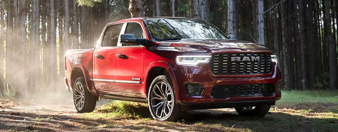 A red 2025 Ram 1500 is shown parked near a forest.