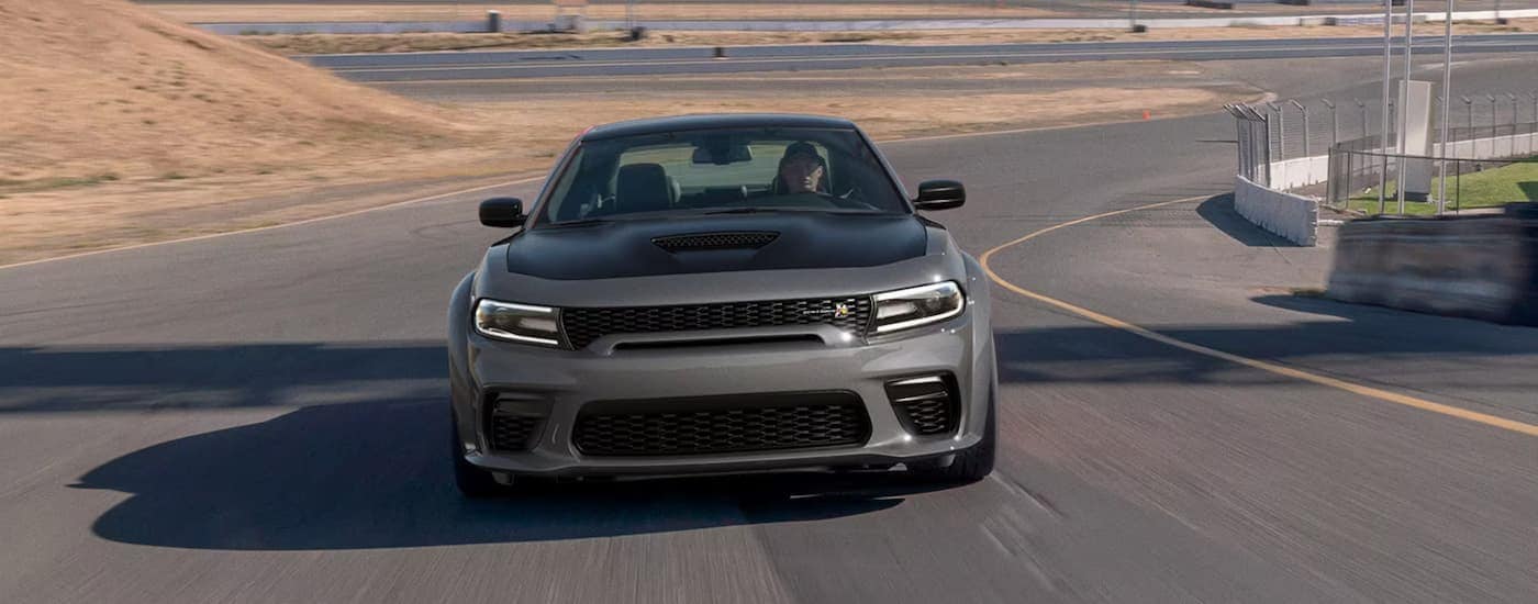 A grey 2023 Dodge Charger Scat Pack Widebody driving on a winding road.
