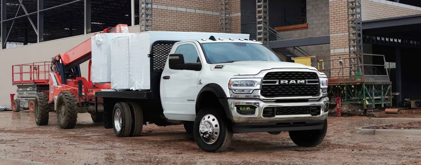 A white 2024 Ram 5500 for sale is being loaded with construction supplies.