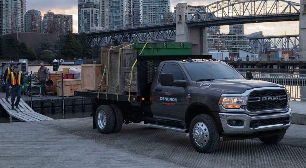 A black 2025 Ram 5500 Tradesman Chassis Cab loaded with cargo at a dock.