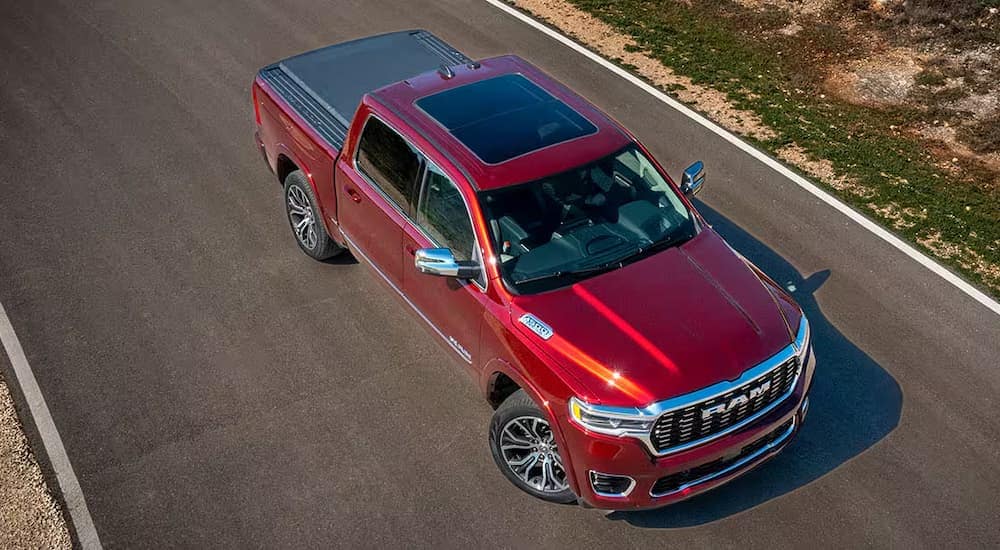 A red 2025 Ram 1500 is parked on a paved road after going to a Ram service center.