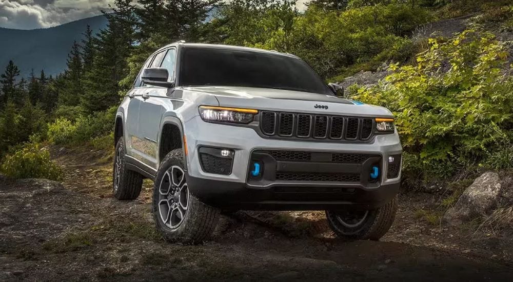 A silver 2024 Jeep Grand Cherokee 4xe is shown off-road after visiting a Jeep dealer
